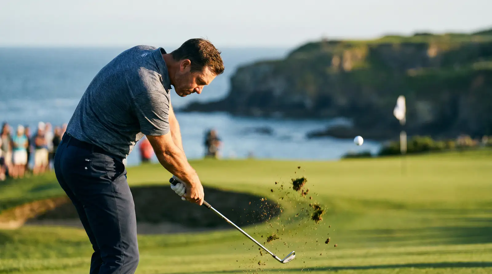 Professional golfer hitting a solid approach shot that lands near the pin during tournament play