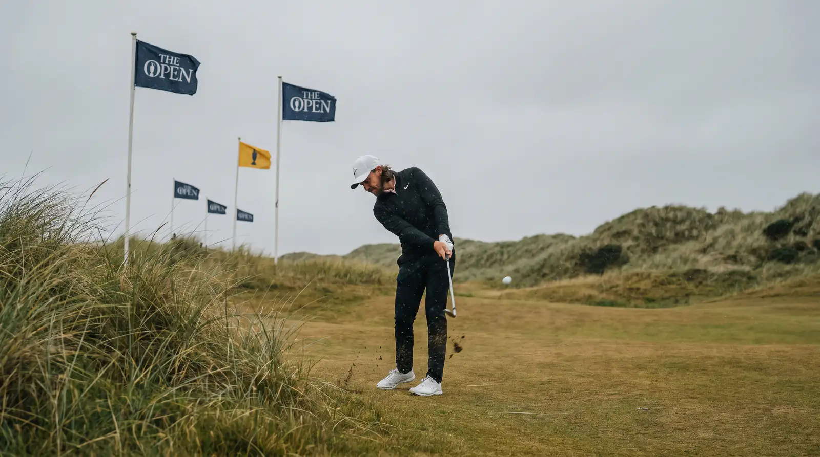 Golfer hitting a low punch shot into strong wind on a links course
