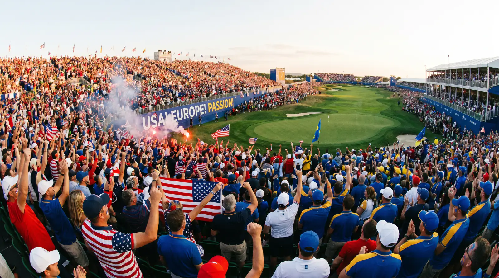 Passionate Ryder Cup crowd in team colours cheering from grandstands with flags and banners
